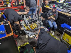 Students Michael Whiddon, Zosia Dupont, and Sarah Herko prepare their robot for another match alongside mentors Frank Bosak, Frank Shively, and Alex Richards.